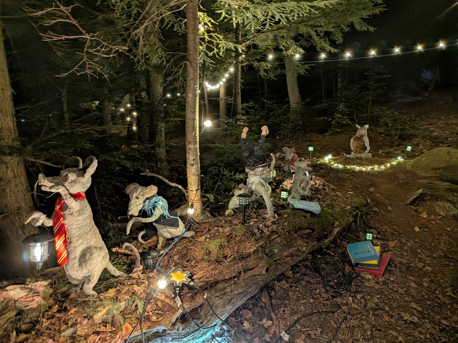 String lights and lanterns in the forest with rat sculptures and a stack of poetry books
